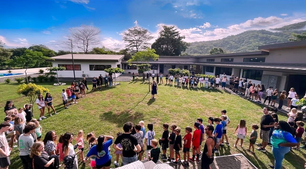 Journey School of Jacó students gathered in a circle on the campus lawn