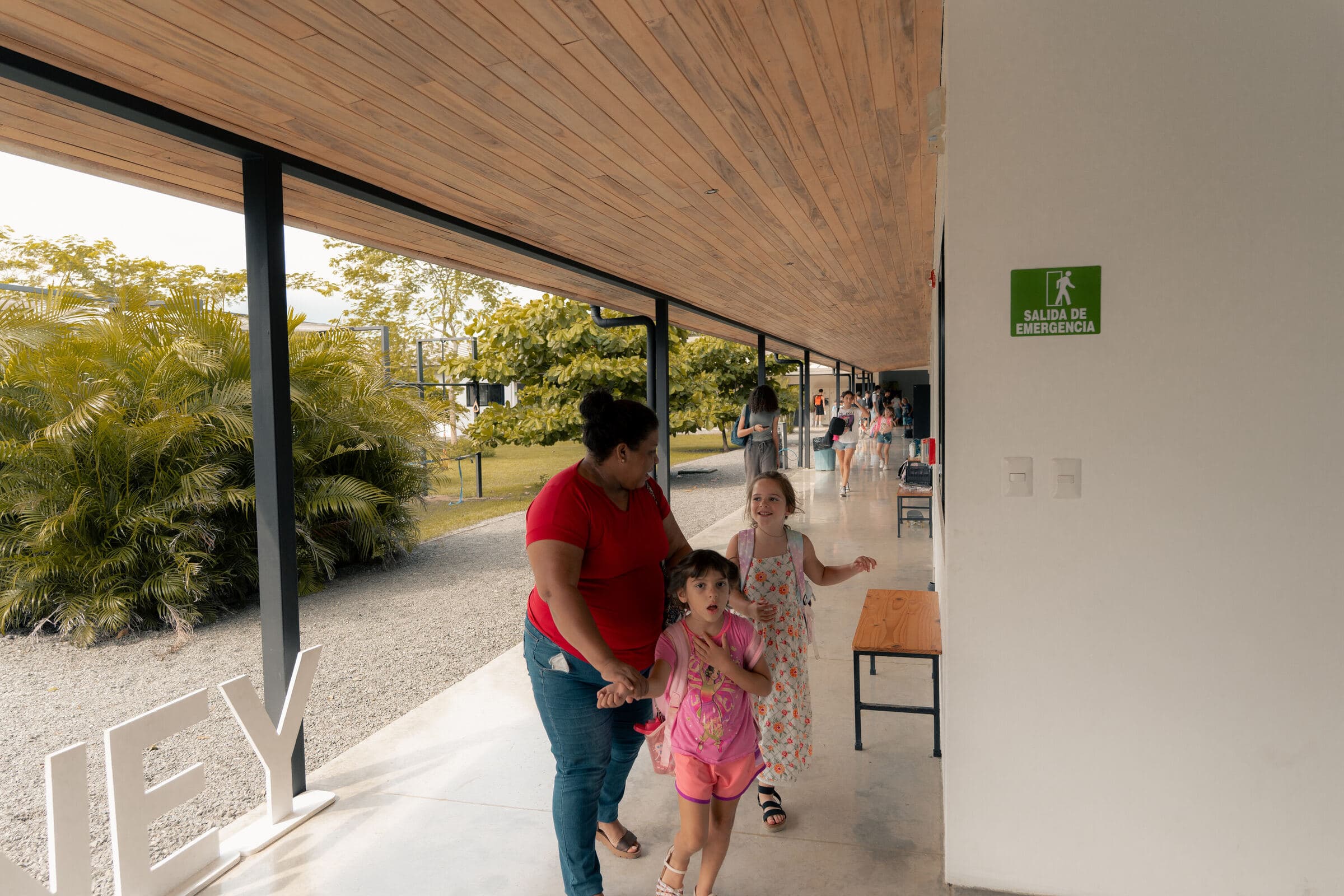 Family walking through a covered campus walkway with wood ceiling